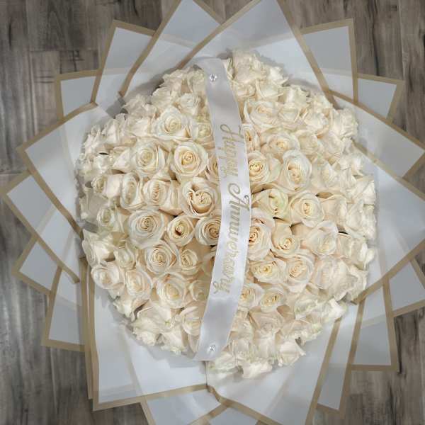 Large bouquet of cream roses wrapped in white paper with a ribbon