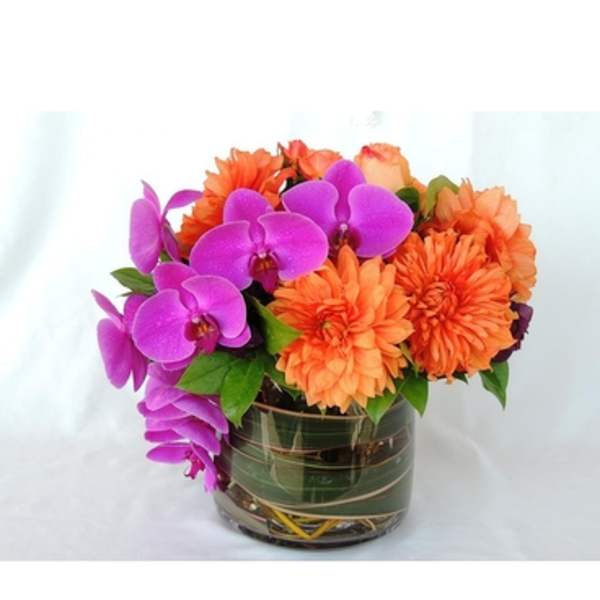 Orange dahlias and purple orchids in a glass vase
