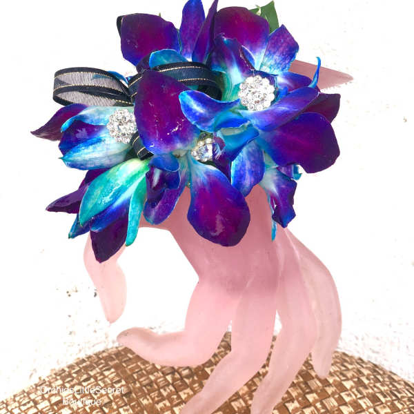 Blue and purple orchid boutonniere on a pink hand-shaped stand