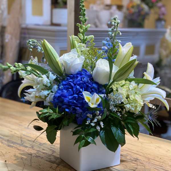 Blue hydrangea and white lilies in a white square vase