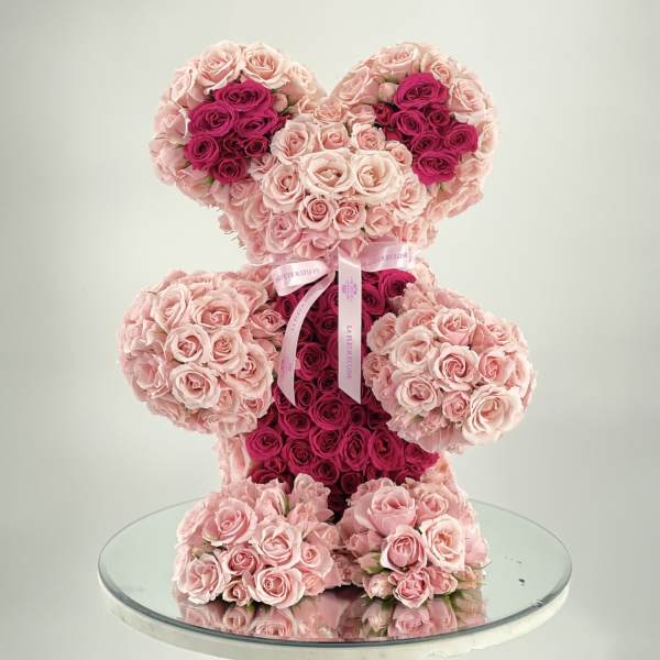 Teddy bear made of pink and magenta roses on a glass table