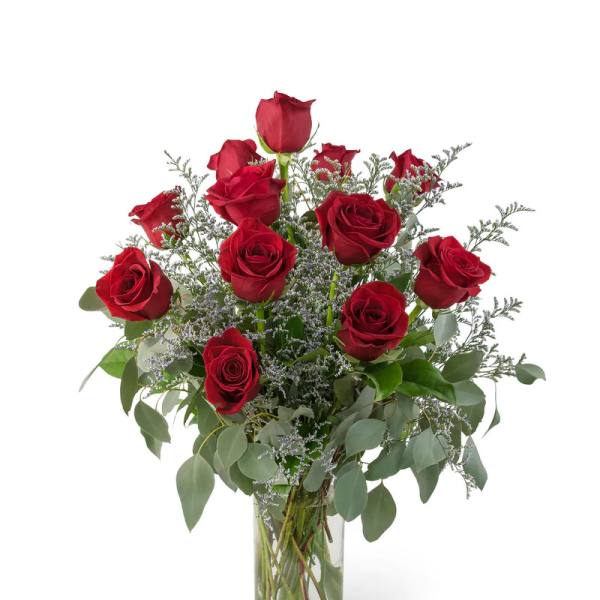 Red roses arranged in a clear glass vase with airy filler and greenery