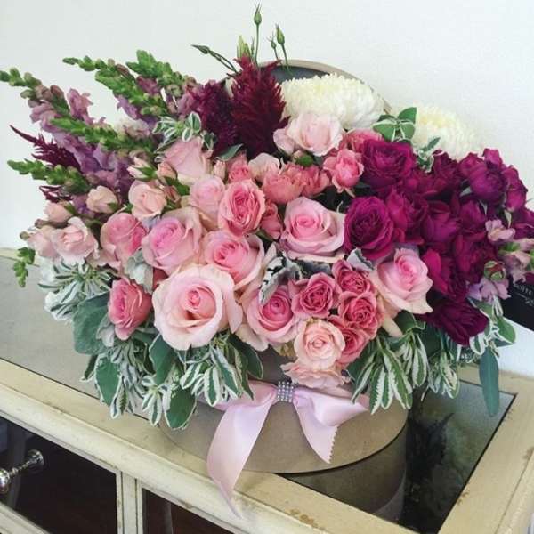 Pink and purple rose bouquet in a round box with a ribbon
