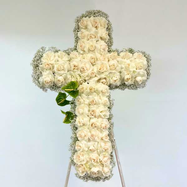 White rose cross-shaped floral arrangement on a stand