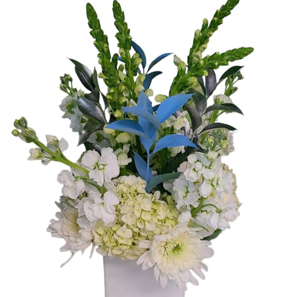 White floral arrangement in a square vase with blue accent leaves