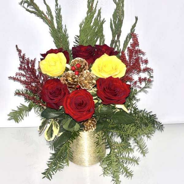 Red and yellow roses in a gold container with evergreen accents