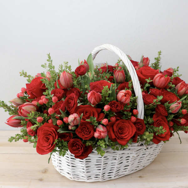 Basket of red roses and pink tulips with greenery