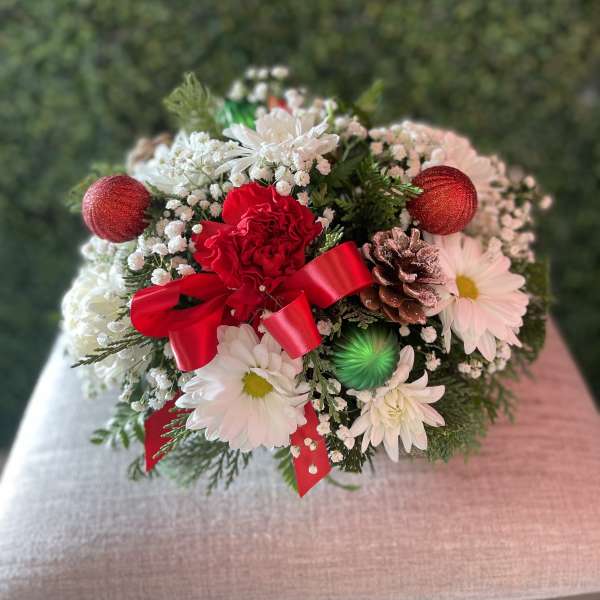 Holiday bouquet with white daisies, red carnations, and a red ribbon