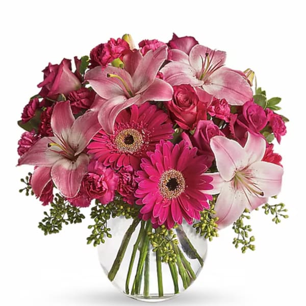 Pink lilies, gerbera daisies, and roses in a clear glass vase
