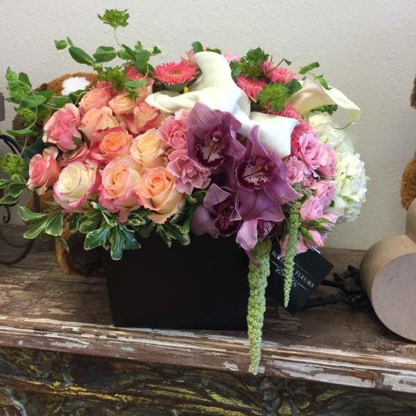 Mixed bouquet of pink roses, purple orchids, and white calla lilies in a black box