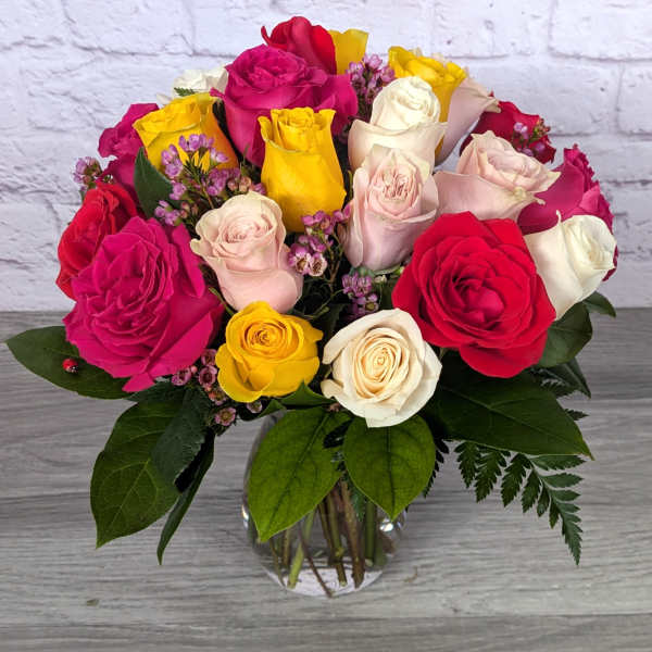 Mixed roses in a clear glass vase with small purple filler flowers