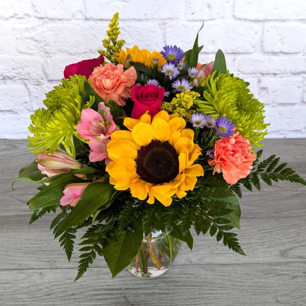 Colorful mixed bouquet with a sunflower in a glass vase