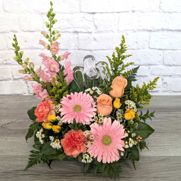Pink gerberas and peach roses arranged with snapdragons in a low container.