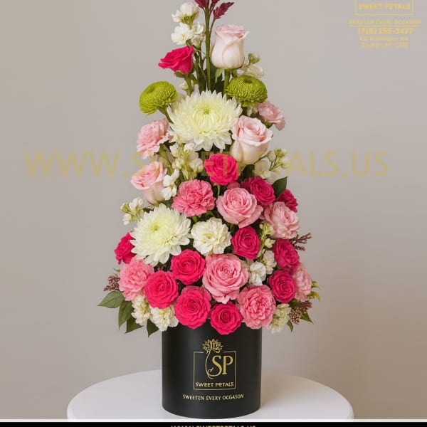 Tall pink and white floral arrangement in a black cylinder box