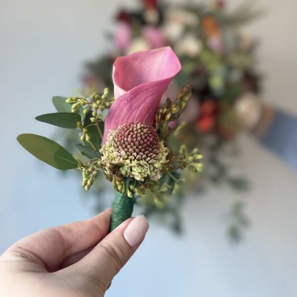 Pink calla lily boutonniere with small green accents