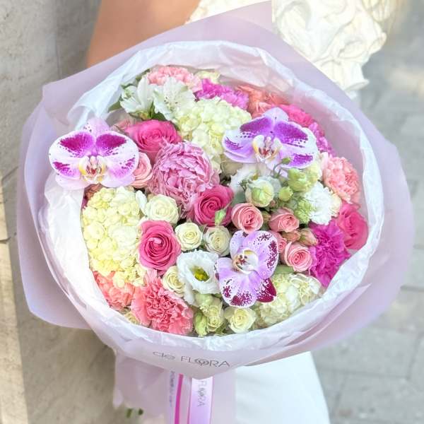 Pink and white mixed bouquet with orchids and roses wrapped in pale paper