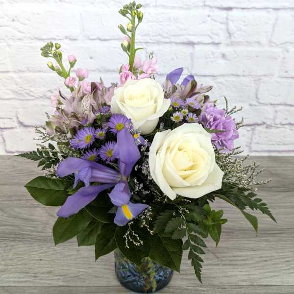 White roses and purple flowers in a glass vase