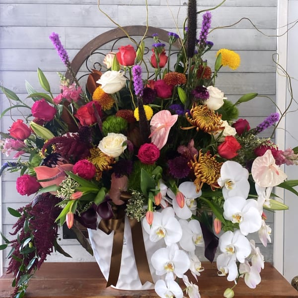 Large mixed floral arrangement with white orchids and colorful roses