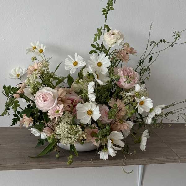 Low floral arrangement with pink and white blooms in a white bowl
