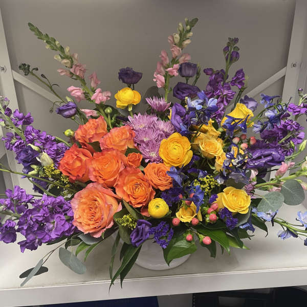 Colorful mixed bouquet in a white vase with purple, orange, and yellow blooms