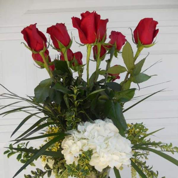 Tall bouquet of red roses and white hydrangeas in a glass vase