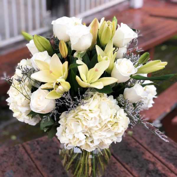 White roses and lilies arranged in a glass vase