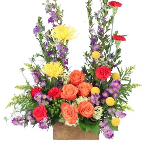Colorful floral arrangement with roses, carnations, and purple filler flowers in a wooden box