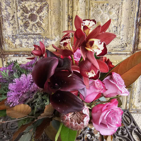Bouquet of pink roses, dark calla lilies, and red orchids