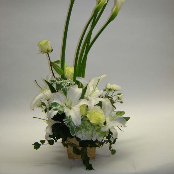 White calla lilies and lilies arranged in a wooden container