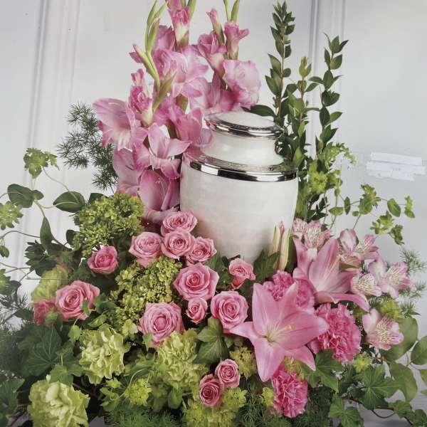 Pink lilies and roses arranged around a white urn