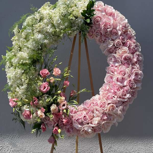 Large floral wreath of pink and white roses on a wooden stand