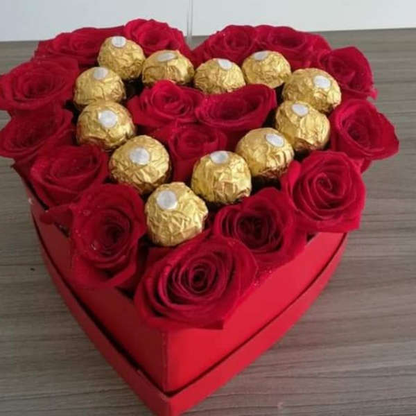 Heart-shaped box of red roses topped with gold-wrapped chocolates
