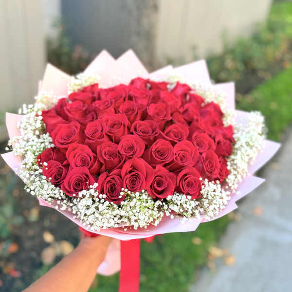 Bouquet of red roses with white baby's breath in pink wrapping