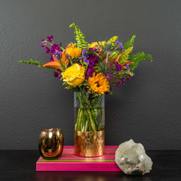 Bright mixed bouquet in a glass vase with a gold base