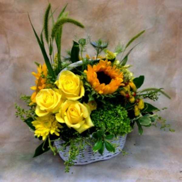 Yellow roses and sunflowers in a white basket