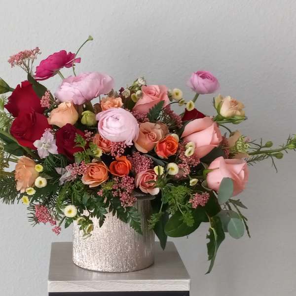 Mixed bouquet of roses and ranunculus in a silver vase