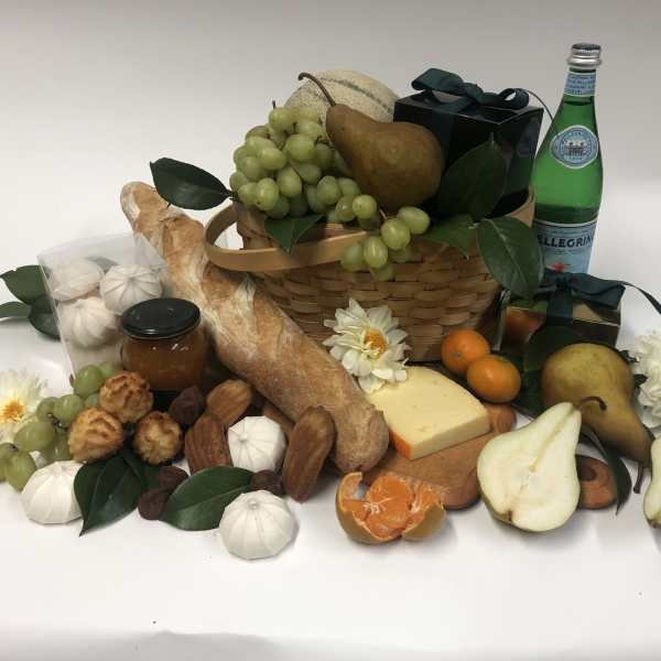 Gift basket with fruit, bread, cheese, pastries, and a bottle of sparkling water