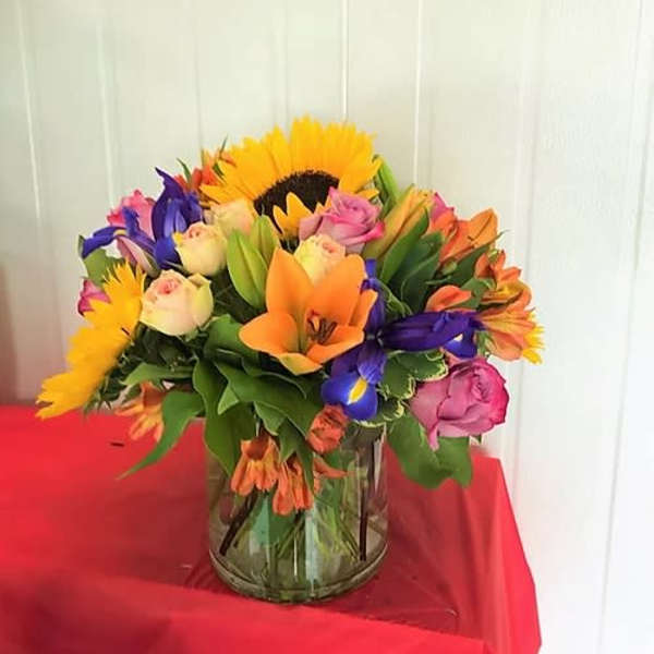 Colorful mixed bouquet in a glass vase with sunflowers and roses