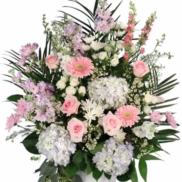 Pink and white floral arrangement in a white urn vase