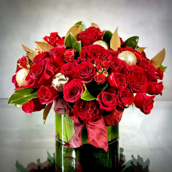 Red rose bouquet in a green glass vase with gold ornaments and ribbon