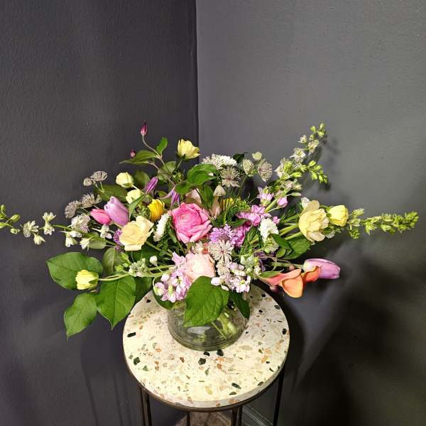 Mixed bouquet of pink, yellow, and white flowers in a glass vase