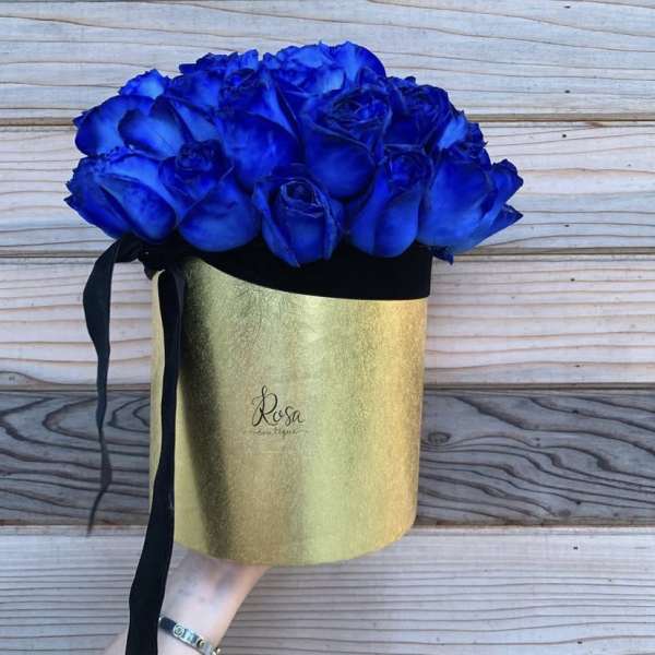 Blue roses in a gold hatbox with a black ribbon