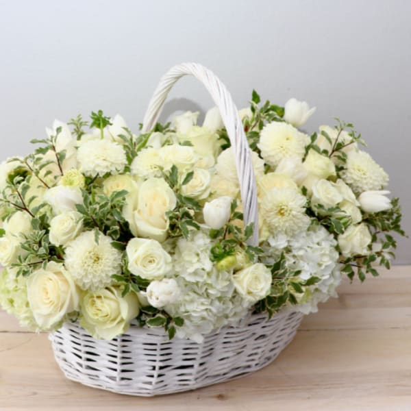 White flower basket with roses, tulips, and mums in a wicker basket