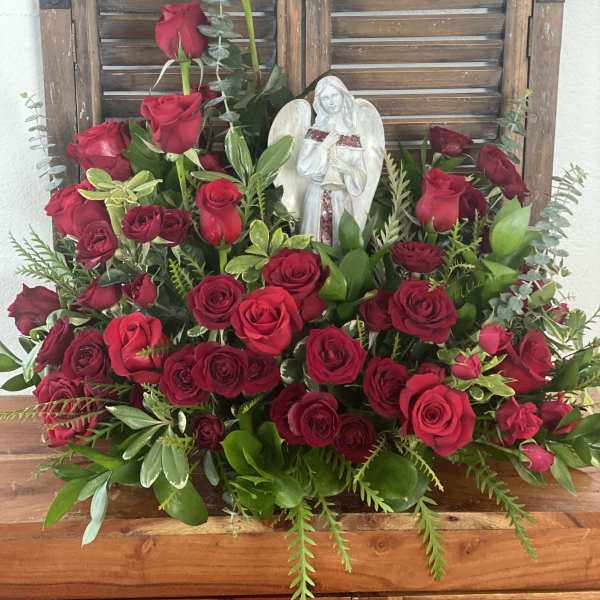 Large arrangement of red roses with an angel figurine