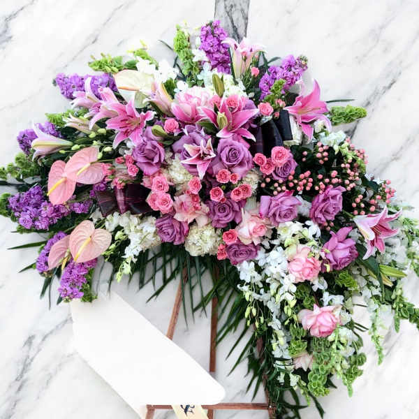 Large pink and purple floral spray with lilies and roses on an easel