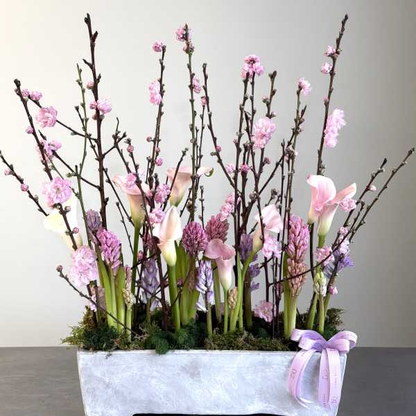Pink calla lilies and blossoms in a rectangular silver planter