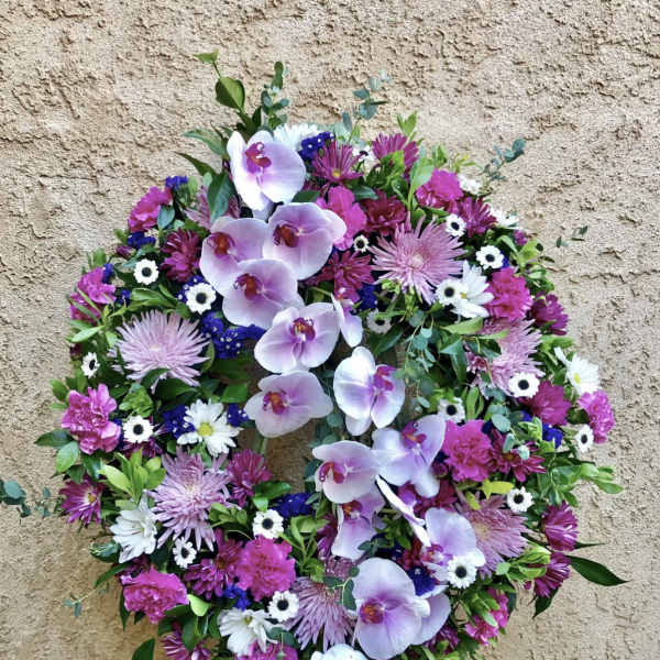 Circular floral wreath with pink orchids and mixed purple-white flowers