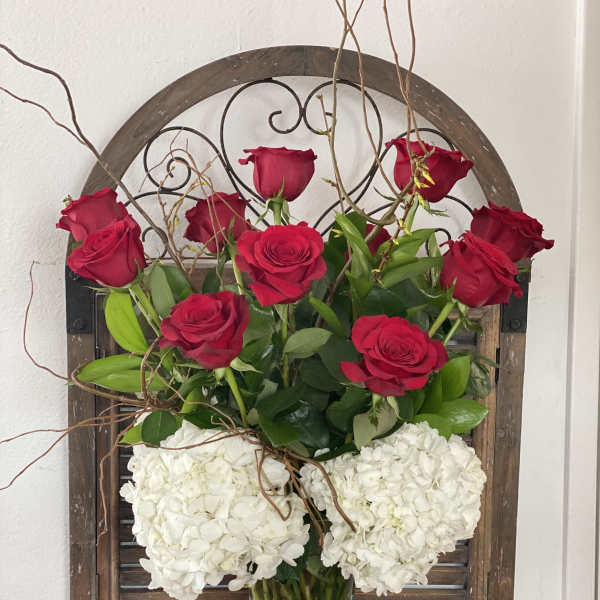 Red roses and white hydrangeas arranged in a clear glass vase