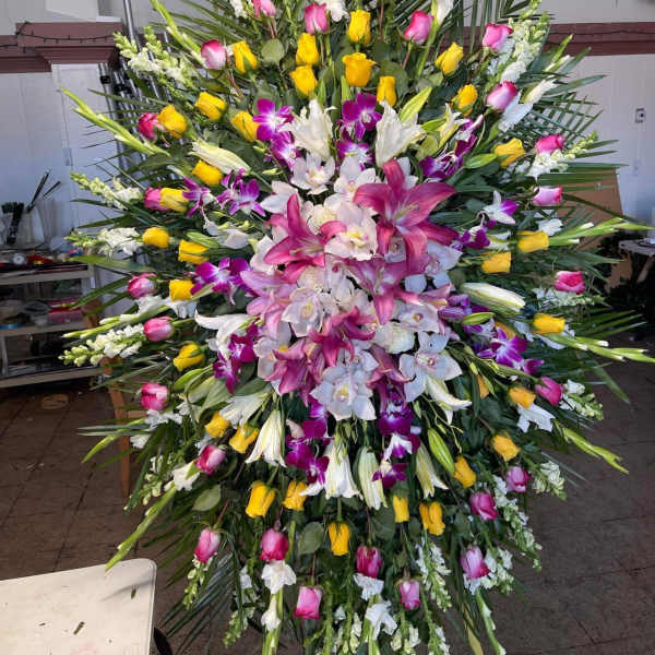 Large standing floral spray with pink, yellow, white, and purple blooms