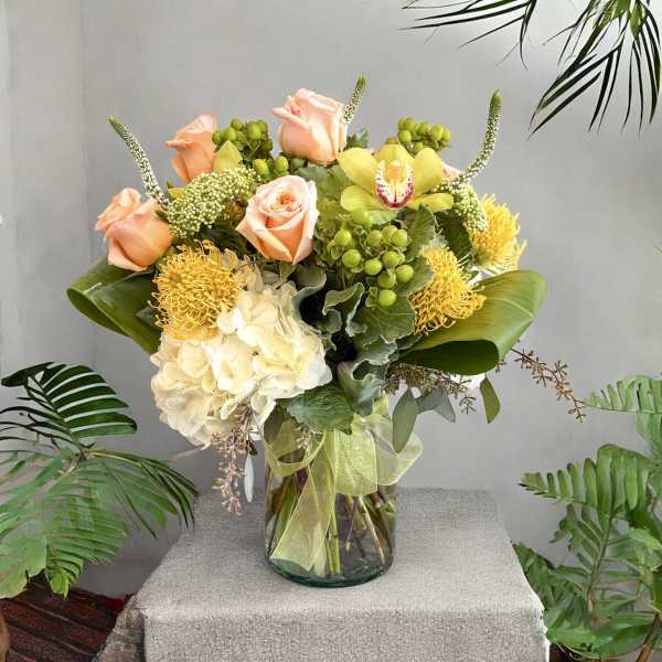 Peach roses and yellow flowers in a glass vase